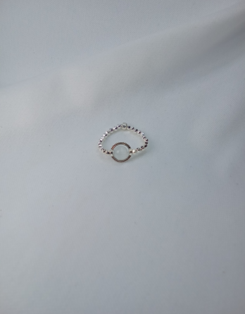 Bague en pierre naturelle pour femme. Un pierre au centre du bijou sertie d'un cercle ciselé. Le tour de la bague est constituée avec des perles effet diamanté en acier inoxydable. Créée en Moselle dans l'est de la France.