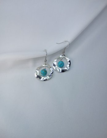 Boucles d'oreilles pour femme en acier inoxydable dans un cercle bosselé qui laisse suspendre une pierre turquoise de 8 mm. Créé en Moselle.