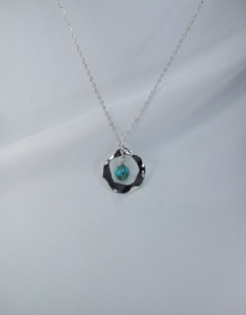 Collier en argent pour femme avec un pendentif rond bosselé qui capture une pierre naturelle de turquoise. Bijou crée près de Metz.